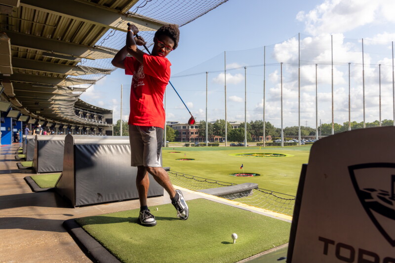 An athlete taking a swing at Topgolf. 