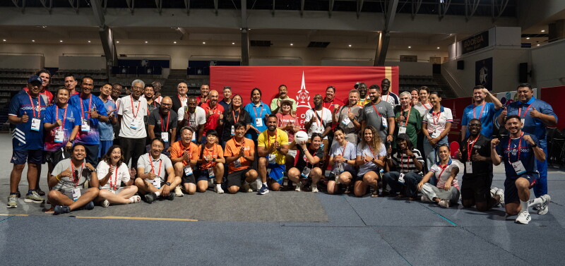 Large group photo in a gymnasium setting, a Special Olympics Unified Football World Cup Paris 2026 banner is behind the group. 