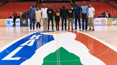 10 Basketball African League members and Special Olympics athletes in a line at half court posing for a photo with a player’s hand on top of a basketball.