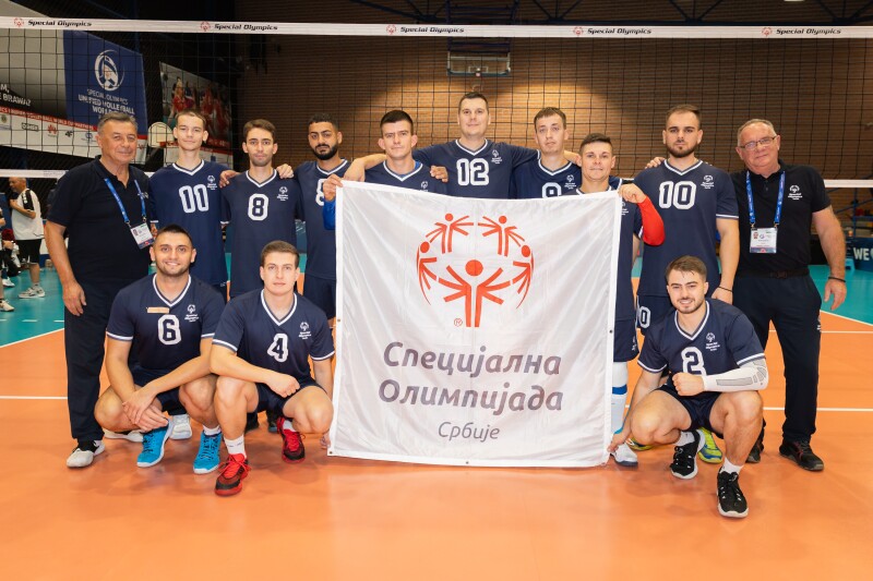 Serbia’s Men’s Team pose on the court while holding the Serbian Special Olympics World Cup Flag