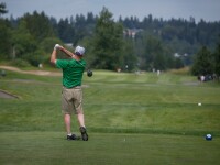 A male golfer just after striking the ball. 