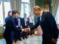 Man shaking athlete's hand in a formal setting. 