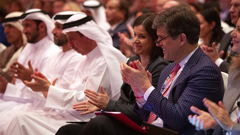 Timothy Shriver and other guests sitting down and applauding in an auditorium.