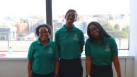 Three young women standing side by side and smiling. 