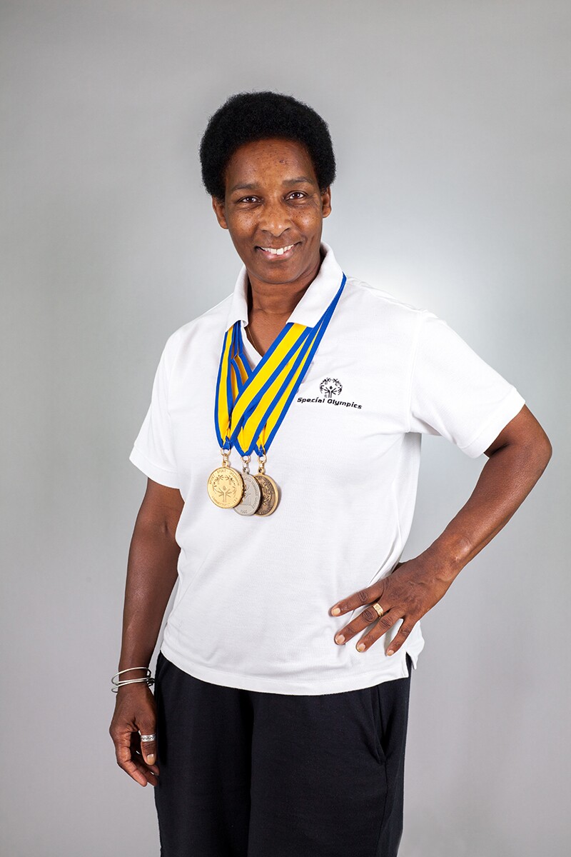Loretta stands and poses for a photo with three medals displayed proudly around her neck.