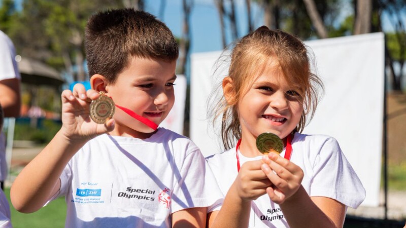  A boy and a girl proudly smile as they display the medals hanging around their necks.