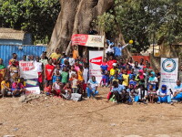 Large group of people standing in front of a tree. 