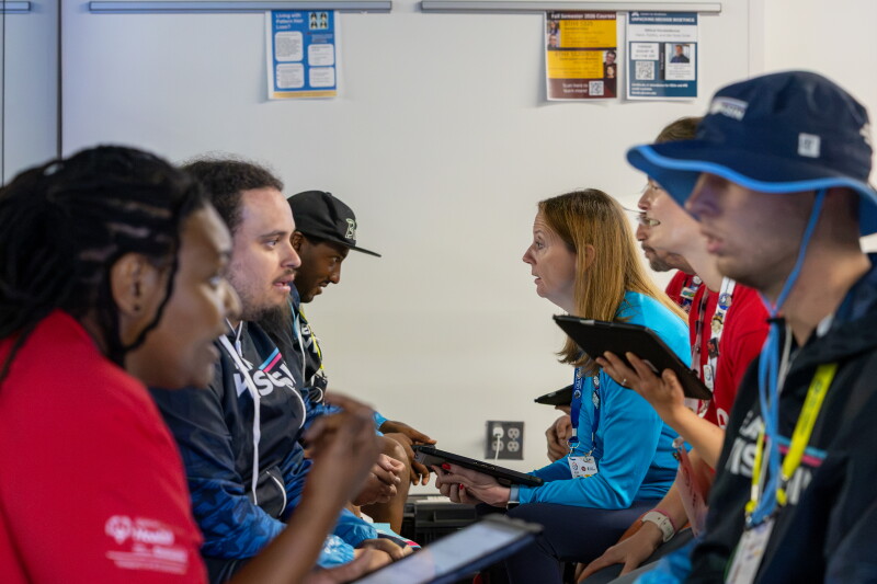 a group of people sitting in two rows across from one another speaking and paying attention to one another. 