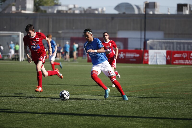 Futbolistas en el campo persiguiendo el balón. 