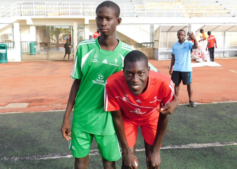 Two young men pose for a photo on a track and field