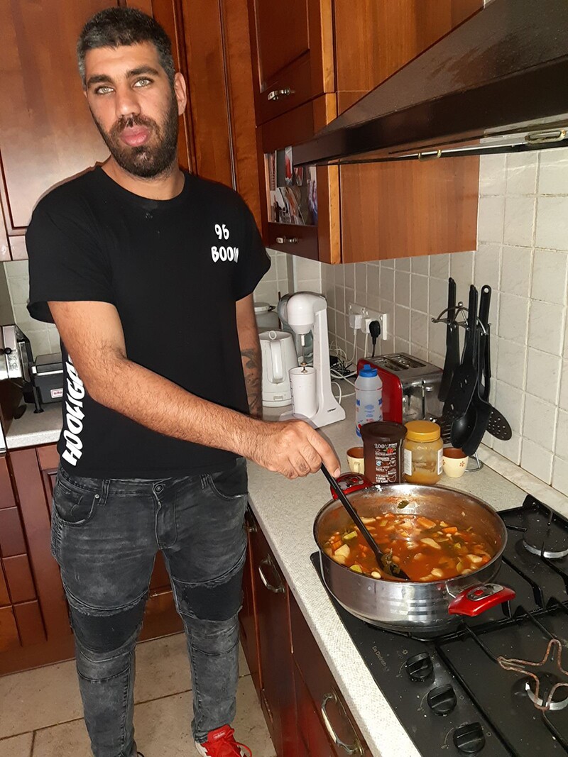 Athlete in the kitchen at the stove stirring slow cooked beans.