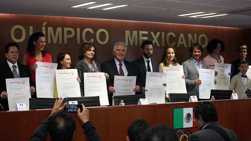 Group of Special Olympics representatives standing at a professional event holding up documents as a group.