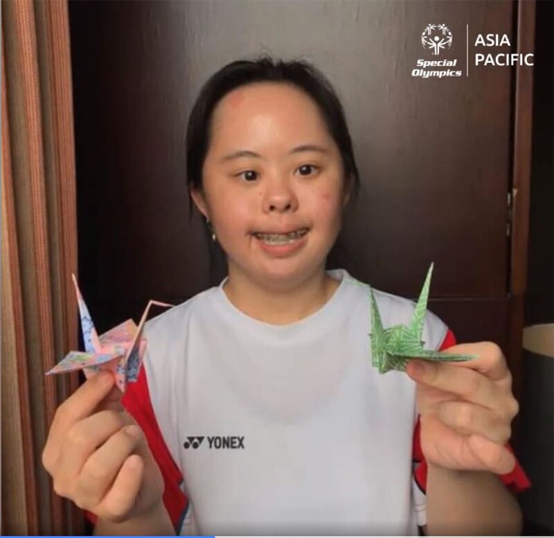 Stephanie holding two paper cranes.