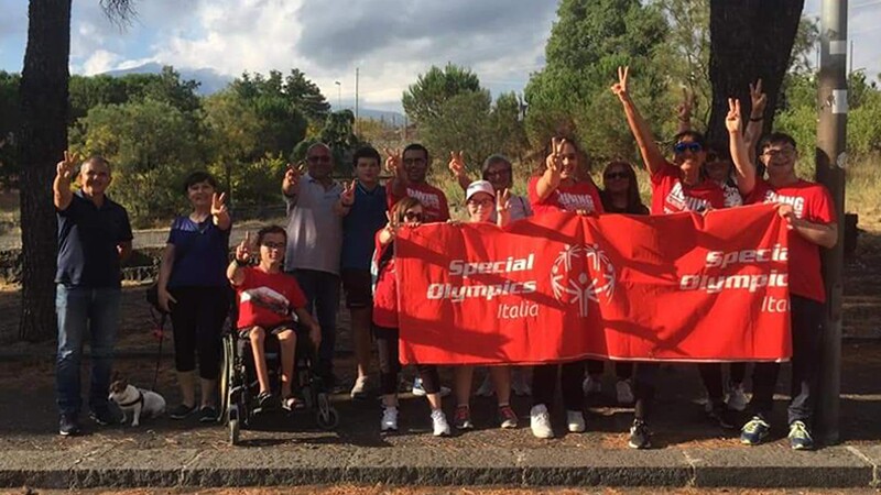 A group of walkers outside holding a Special Olympics Italia banner.
