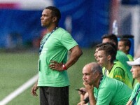 Man in green shirt standing with others sitting on a bench