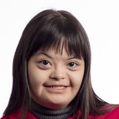 Brina smiling for a professional photo. she is wearing a red Special Olympics long sleeve polo.