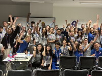 A group of adults in a classroom setting standing in two rows for a group picture. 