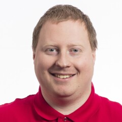 Ian standing for a professional photo wearing a red long sleeve Special Olympics polo.