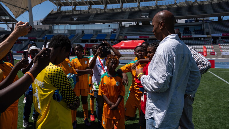 A man speaks to a group of footballers in a football stadium