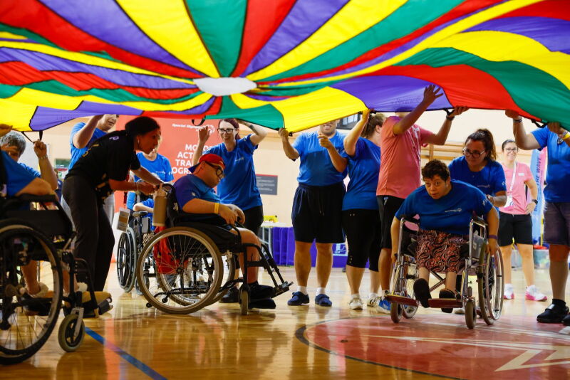 A group of athletes waving a huge, colourful cloth over their heads