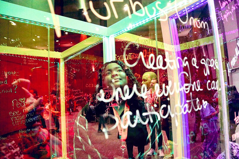 Young woman looking up at writings on a glass wall and smiling.