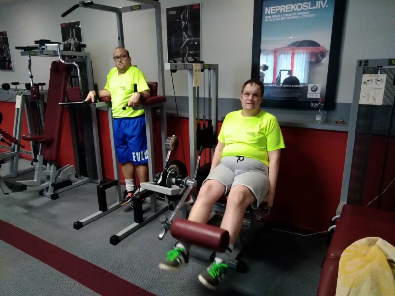 Two Special Olympics athletes using equipment in a gym. 