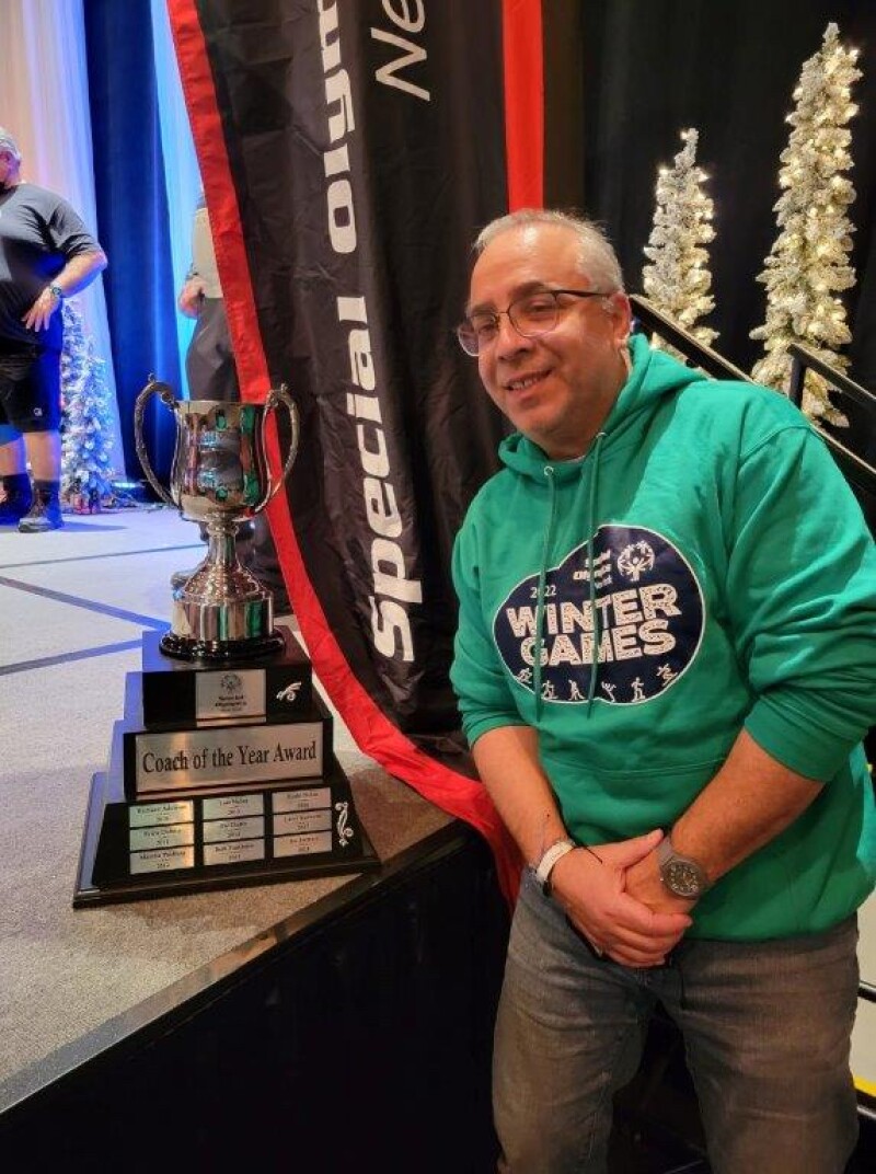 A man poses with a trophy. 