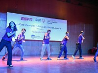 Six young adults on stage putting on a performance. The sign in the background reads Unified Champion Schools Distinction Awards. 