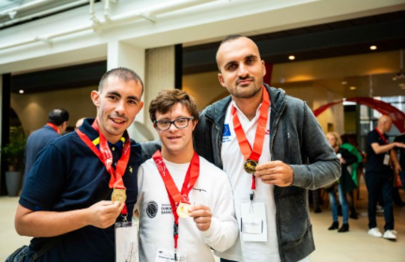 Three men holding medals with red ribbons stand together facing the camera.