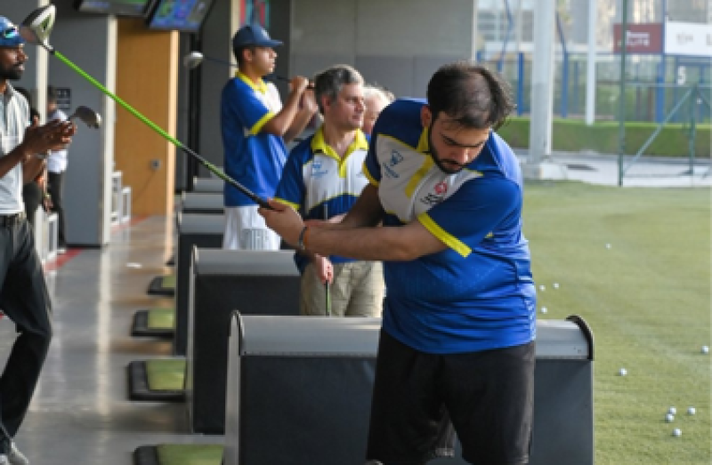 People lined up playing topgolf. 