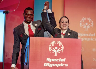 Nyasha and Renee standing behind a podium and holding one another's raised hand. 