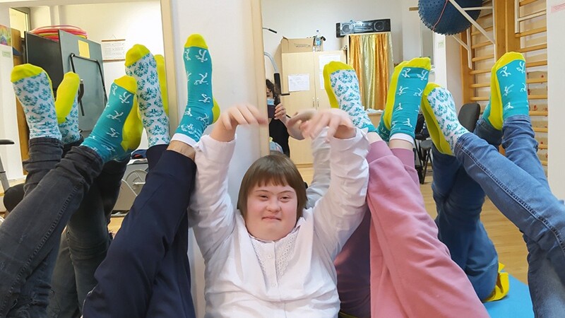 A young athlete in the middle of students showing off their socks in support for Socksy Day. 