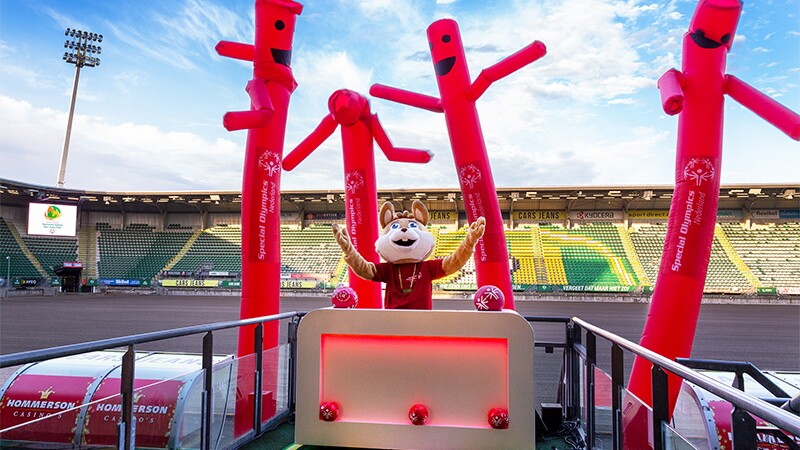 Mascot DJing on a platform in a stadium.