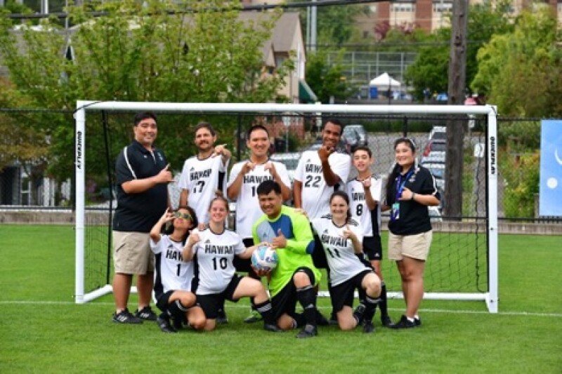 A group of Special Olympics soccer athletes pose for a photo in front of a soccer goal.