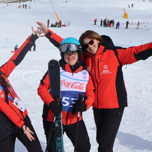 A athlete standing with two people smiling and enjoying the day outside in the snow. 