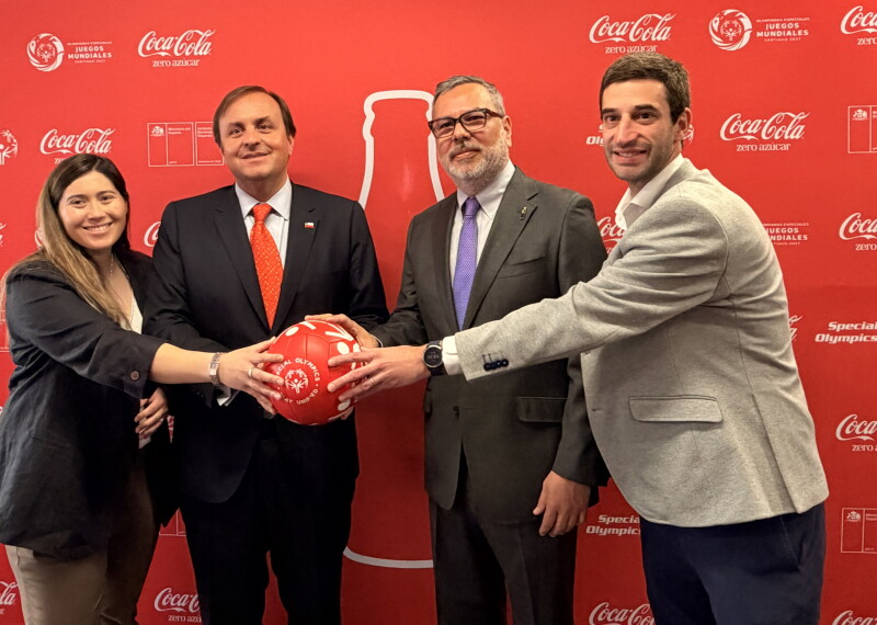 Four people posing for a photo while holding a Special Olympics-branded football.