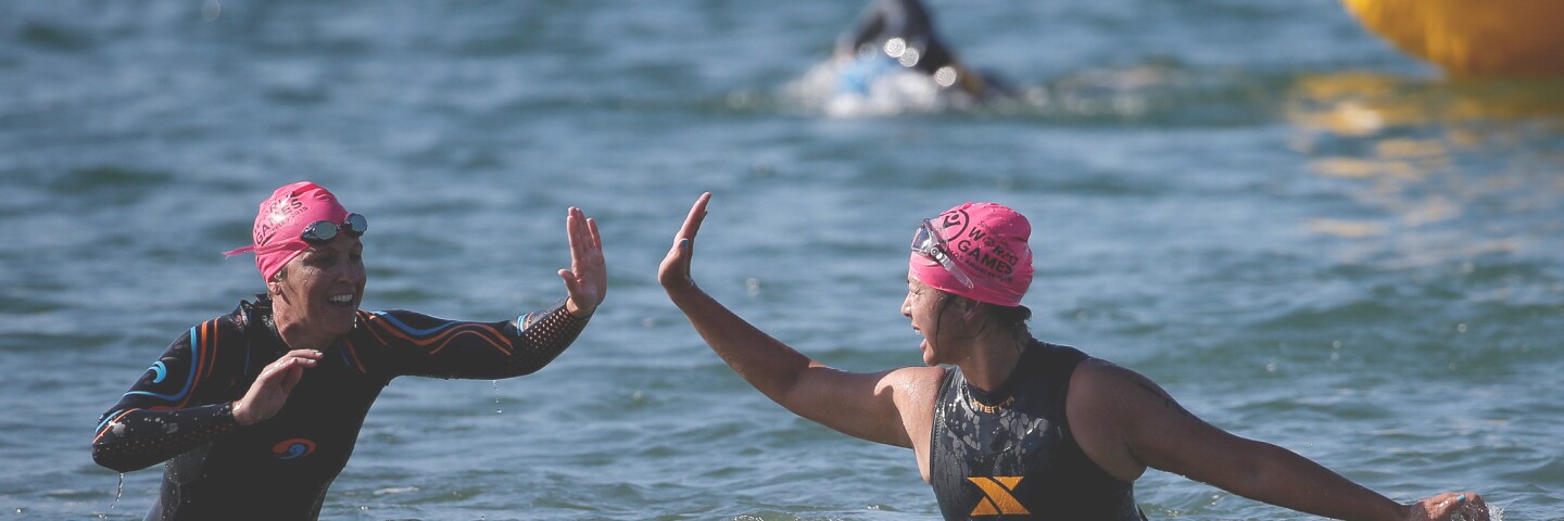 Two female players give one another a high-5 as they come out of the water. 