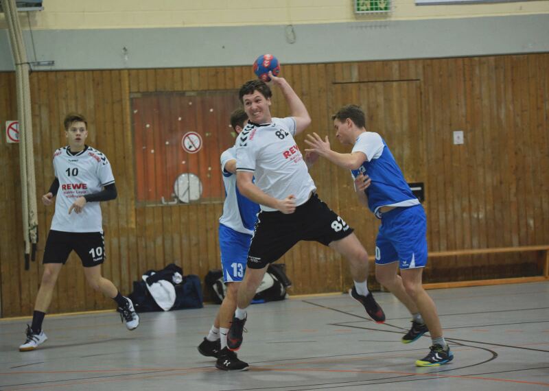 Player prepares to throw the ball while two players from the opposing team attempt to block.