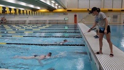 Young man swimming toward a coach at the end of the pool. 