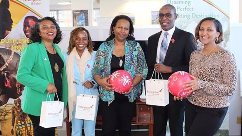 five people standing holding draw-string bags and Special Olympic soccer balls