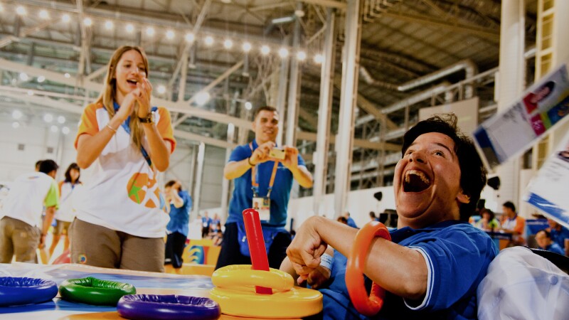 Athlete works with rings as as a coach cheers him on.