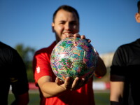 Young adult athlete holds and shows off a football. 