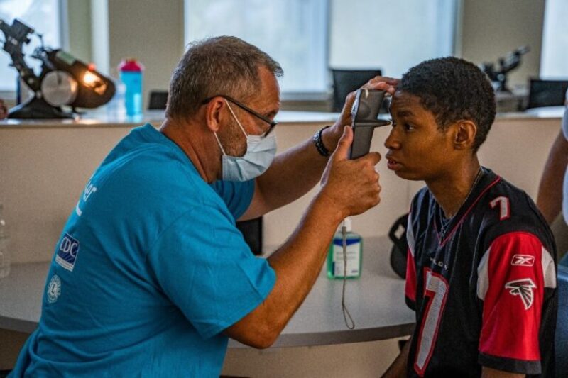 An eye specialist examines a young man's eyes. 