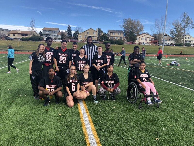 Coach Warner (first on the left) standing with her flag football team on the field.