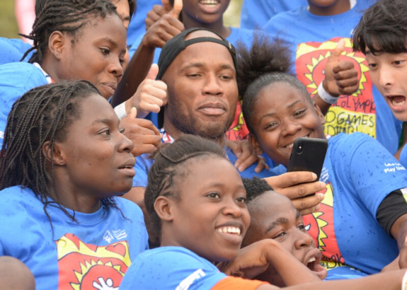 Didier Drogba surrounded by athletes for a group photo. 