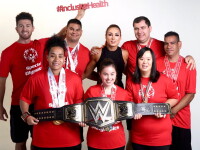Group of athletes standing together holding the WWE championship belt