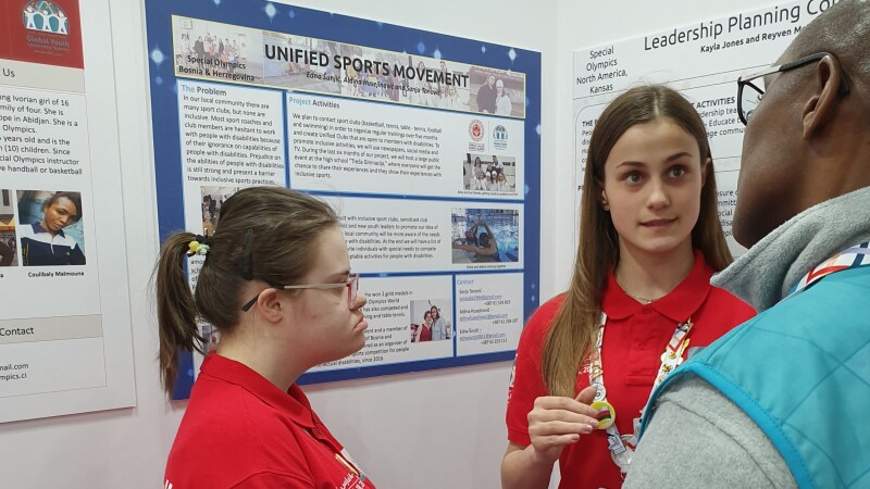 Two athletes talking to a volunteer. 