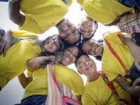 A ground of athletes standing in a circle looking down and smiling. 
