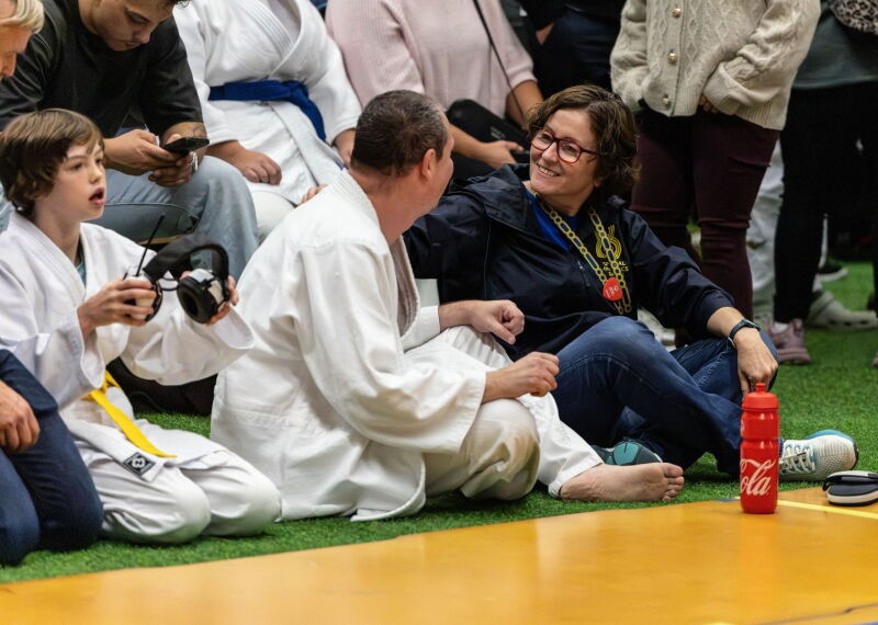 A woman and man look at each other at the sidelines of a judo match. 