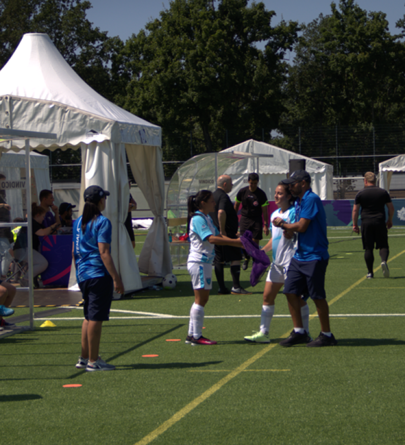 Two players making a substitution with coaches nearby